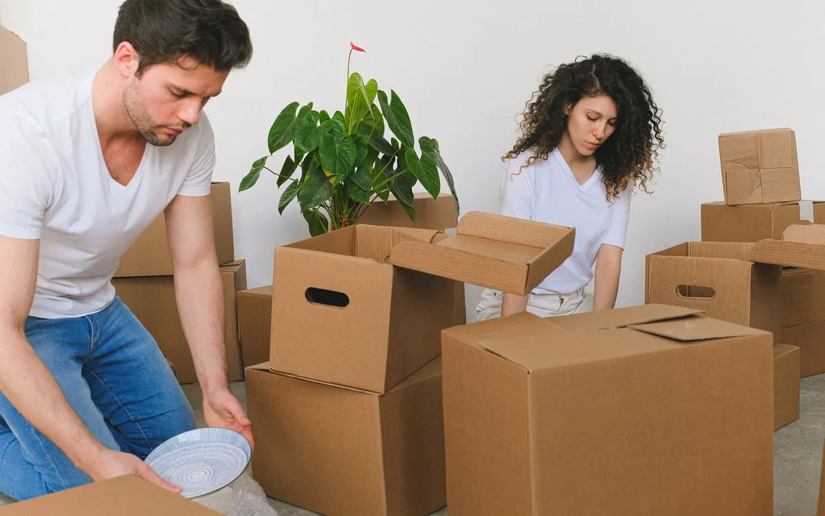 Zwei Personen sortieren Kartons und Hausrat in einem Wohnzimmer