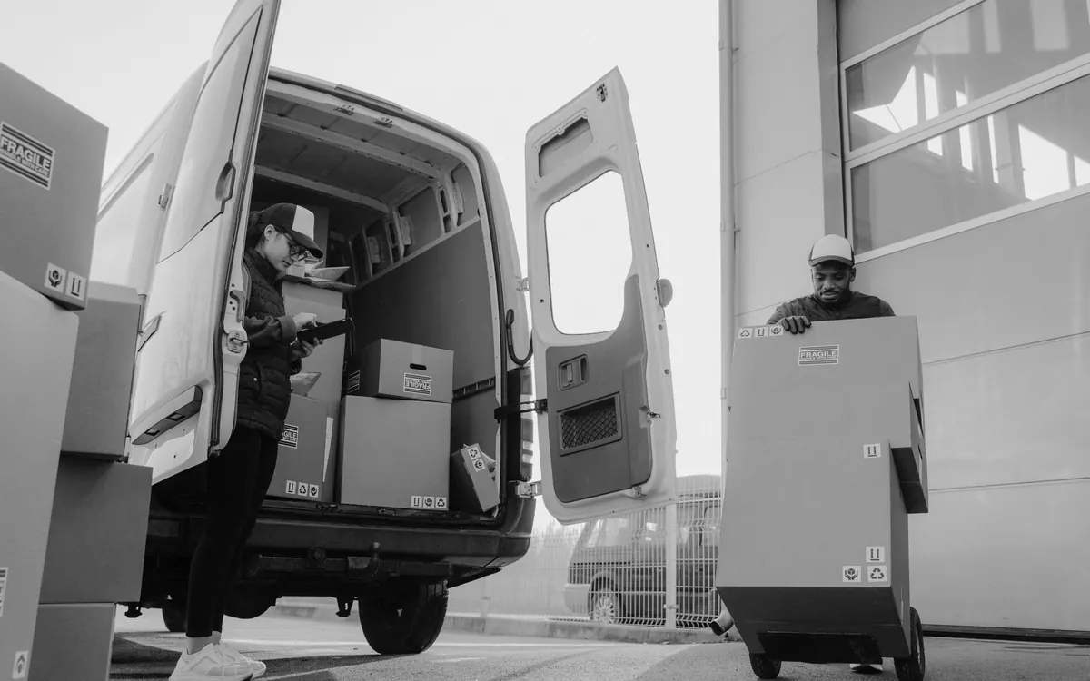 Helfer laden Kartons aus einem offenen Transporter