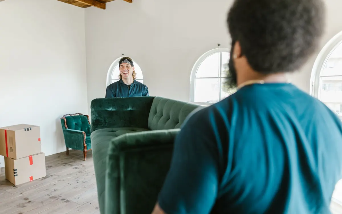 Zwei Umzugshelfer tragen ein Sofa durch eine Wohnung
