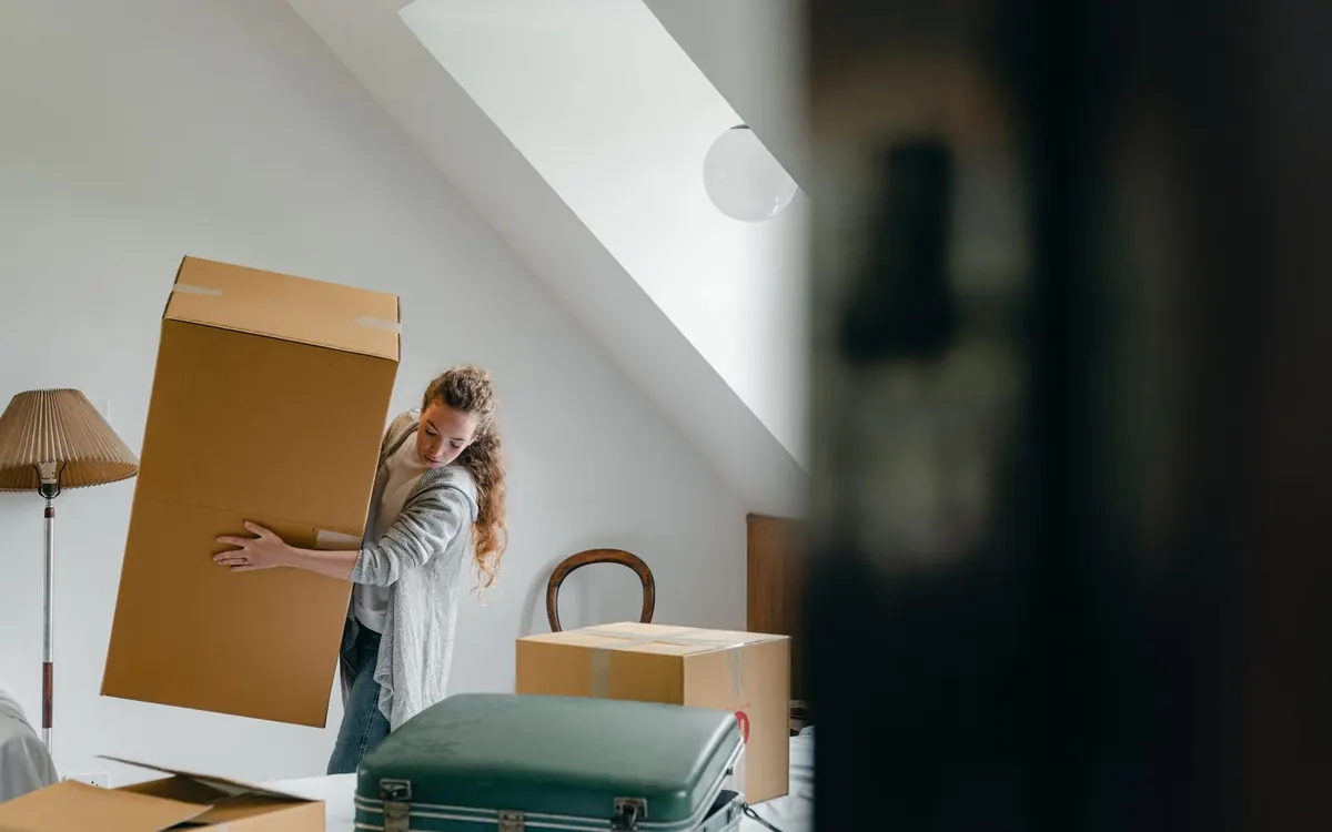 Eine Person prüft Notizen zwischen gepackten Umzugskartons